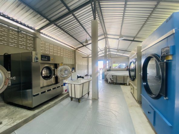 Industrial laundry factory for sale in Pattaya with washing machines, dryers, and ironing equipment included