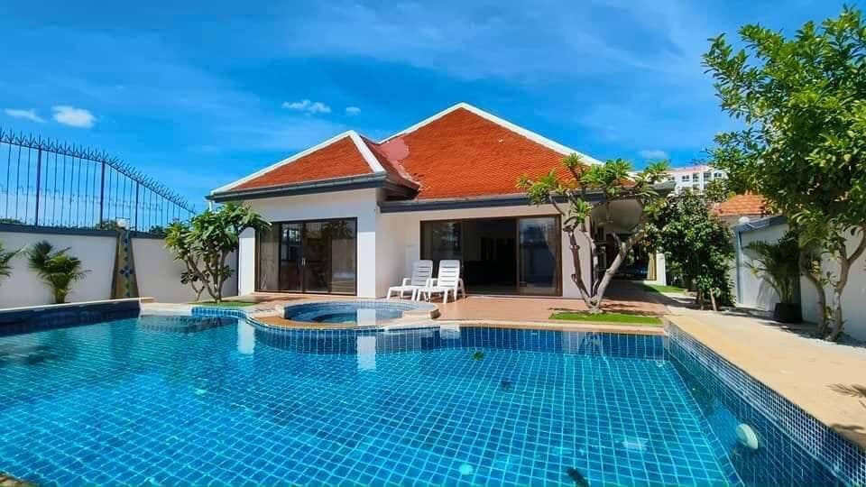 A modern 4-bedroom house in Jomtien, Pattaya, with a spacious front yard and elegant facade.