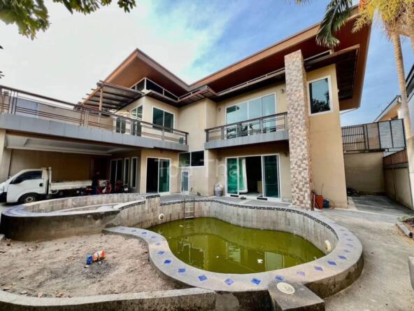 Modern semi-detached house in Piam Mongkol Village 3, Huai Yai, featuring a spacious layout and private swimming pool surrounded by lush greenery.