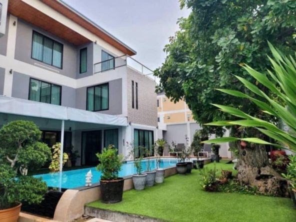 View of a luxurious 5-bedroom house in Soi Khao Talo, Pattaya, with a large private swimming pool and lush garden.
