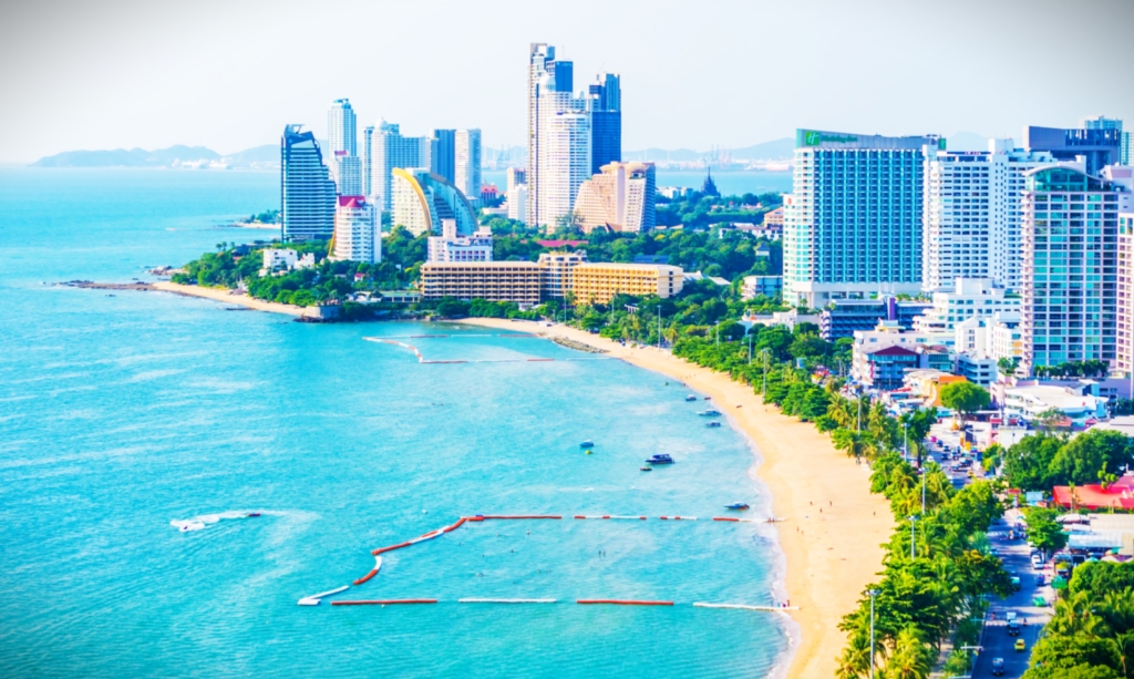 Modern residential buildings along Jomtien Beach, Pattaya, with palm trees and a sunny beachfront view.