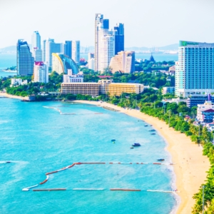 Modern residential buildings along Jomtien Beach, Pattaya, with palm trees and a sunny beachfront view.