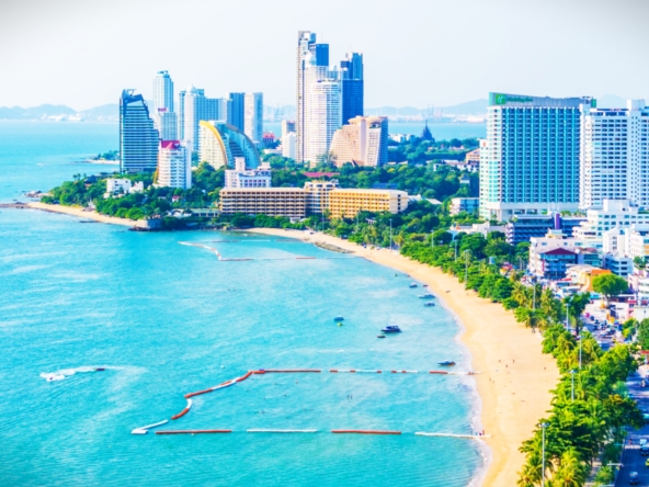 Modern residential buildings along Jomtien Beach, Pattaya, with palm trees and a sunny beachfront view.