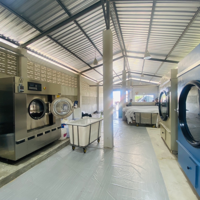 Industrial laundry factory for sale in Pattaya with washing machines, dryers, and ironing equipment included